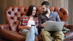 young couple sitting on sofa and using gadgets Stock Footage