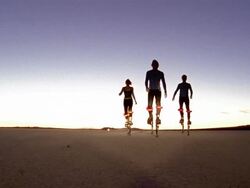 Low angle wide shot woman and two men walking in desert on skyrunners towards CAM Stock Footage