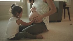 Beautiful ethnic mother letting her toddler feel her pregnant stomach Stock Footage