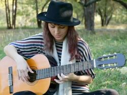 Young woman playing guitar on summer day in park outdoors. Stock Footage