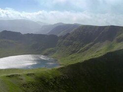Aerial view over Striding Edge to reveal Red Tarn lake at the foot of Helvellyn in the Lake District / Cumbria, England Stock Footage