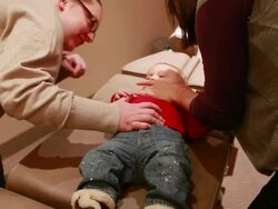 MS Female chiropractor adjusts babies neck on chiropractic bed as mother protects and soothes / Toronto, Ontario, Canada Stock Footage