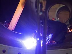 Medium Long Shot steadicam tracking,right , A welder uses an arc welder to weld a seam in a confined area. /  Stock Footage