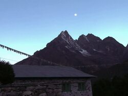 Prayer flags flying above a stone building in the Himalayas. Stock Footage