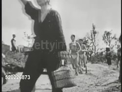 1945: OKINAWA, JAPAN: HELPING CIVILIANS: US Soldier carrying older woman down hill. People, some w/ little clothing, walking road. Male being carried in litter. Pacific Theater, WWII, World War II. Instructional Video