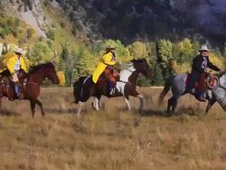 Cowboy and Cowgirls galloping on horseback through the mountain foothills Stock Footage