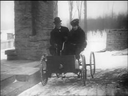 B/W 1910s Henry Ford and wife Clara driving up to house in early car "quadricycle" / documentary Stock Footage