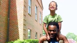 MS Laughing young boy riding on fathers shoulders walking through park on summer afternoon Stock Footage