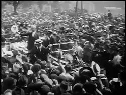 B/W 1917 high angle PAN Woodrow Wilson standing in moving car in dense inaugural parade waving hat Stock Footage