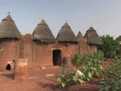 Wide Shot static - A doorway leads into a hut with four thatched roofs. / Benin Stock Footage