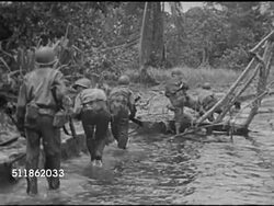 1942: PACIFIC FRONT: Behind soldiers cautiously wading water's edge near clearing. WS Aircraft parked beyond palm trees. VS US Solders firing artillery in open field, pushing bomb through grass toward bomber aircraft. Pacific Theater, Campaign, WWII Instructional Video