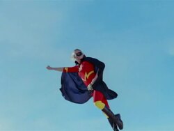 Low angle wide shot young blonde woman in mask, cape, and superhero costume in midair simulating flying after jumping on trampoline / Las Vegas, Nevada Stock Footage