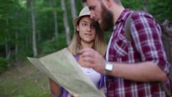 Young hipster couple backpacking lost in forest Stock Footage