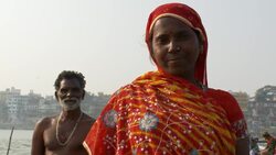 A woman in a saffron veil and a shirtless man stand near the Ganges River in Varanasi. Stock Footage