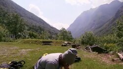 Wingsuit flier packs canopy carefully in landing meadow Stock Footage
