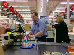 MS Shot of old employee at his cashier desk passing products to clients and woman behind him laughing / Minneapolis, Minnesota, United States Stock Footage