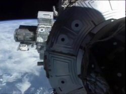 High angle long shot astronaut climbing out of a hatch on the International Space Station Stock Footage