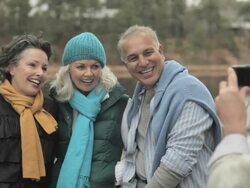 Mature man taking photograph of friends and showing them the picture Stock Footage