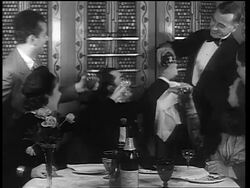 B/W 1933 man in formalwear pouring drinks for people sitting at table / end of Prohibition Stock Footage