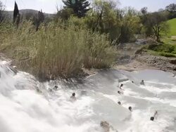 WS View of Sulphurous water plunges in a waterfall in hot springs where people relaxing in thermal pools / Saturnia, Tuscany, Italy Stock Footage