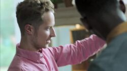 Young man admires denim shirt and chats with store employee in clothing shop Stock Footage