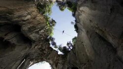 Man traverses highline stretched above deep canyon,gorge Stock Footage