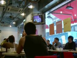 MS Shot inside cafe with people watching TV screen / Hong Kong, China Stock Footage