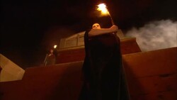 Robed, masked monks wave burning torches as they stand in front of a temple where smoke billows past. Stock Footage