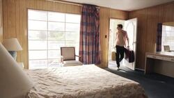 Young couple arrive at Vegas motel, guy jumps on bed and young woman falls on top of him Stock Footage