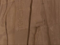 Medium Close Up, tilt-up - Ancient Egyptian drawings cover a stone wall Stock Footage
