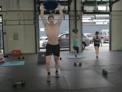 Camera tracks in on Casey as he performs series of overhead lunges; Carly performs overhead lunges in background. Stock Footage