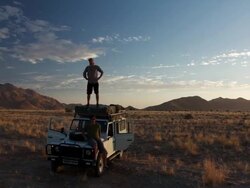 MS T/L Shot of Desert campers survey landscape from roof of all terrain vehicle towards dusk with mountains in back side / Naukluft, Windhoek, Namibia Stock Footage
