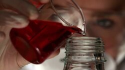 Scientist pouring red liquid into bottle Stock Footage