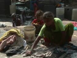 WS PAN Children and adults washing clothes beside street sewer / Dharavi, Mumbai, India Stock Footage