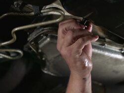 CU SLO MO  Mechanics turning screw and draining oil from oil pan and oil pouring onto hand  / Bergenfield, , New Jersey, USA  Stock Footage