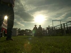 Two cowboys walk in backlit in a rodeo stadium Stock Footage