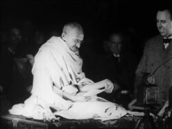 B/W 1931 Gandhi sitting on platform speaking as man stands by him / Geneva, Switzerland / newsreel Stock Footage