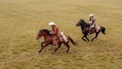 AERIAL Two people riding galloping horses across a meadow Stock Footage