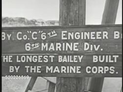 1945: OKINAWA, JAPAN: US Supply truck driving into Naha port. 'Longest Bailey' sign (6th Marine Division Company C) LS Marine built Bailey bridge w/ jeep driving over. Pacific Theater, WWII, World War II. Instructional Video