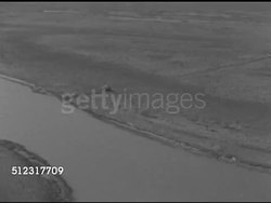 1952: OFFSHORE DRILLING: SHALLOW WATER: AERIAL WS Moving along channel of coastal wetlands w/ drilling rig derrick off channel, TU XWS Long channel cut up through marshland.   Marshes, Gulf Coast, Louisiana, petroleum production, Global Warming Instructional Video