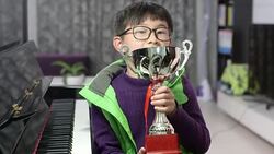 boy holding silver medal cup by the piano Stock Footage