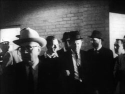 B/W 1963 slow motion Jack Ruby shooting + killing Lee Harvey Oswald indoors / newsreel Stock Footage