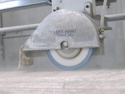 CU of industrial diamond cut blade in protective metal housing cutting through stone slab with water injection to cool off the cut edge  / Thousand Palms, California, USA Stock Footage