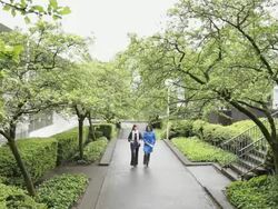 WS TD Two women walking on sidewalk through the urban park / Portland, Oregon, USA Stock Footage