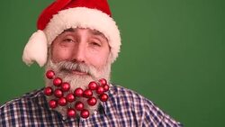 Senior adult man with a beard in elegant hat of Santa Claus looking into the camera and have fun singing shaking his head Stock Footage