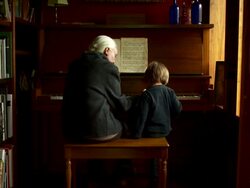 Full shot. Slow push in on grandmother and grandson playing the piano. Stock Footage