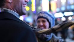 Young couple in love kiss and hold each other close while gazing up at the bright lights of Times Square Stock Footage