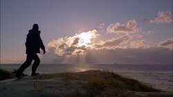A partially silhouetted man walks on a sand dune to look out over the North Sea. Stock Footage