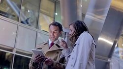 Businessman and businesswoman using digital tablet outside urban building Stock Footage