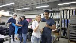 Fashion designers discussing over a document and operators stand at the back Stock Footage